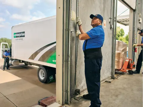 A worker prepares a loading bay at a delivery facility as boxes are loaded onto an Enterprise Flex-E-Rent van.
